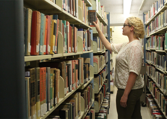 Female student browsing stacks in campus library