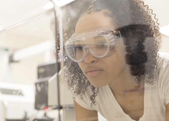 An FDU student wearing safety goggles in a lab environment